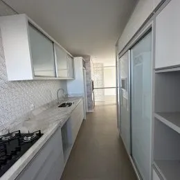 Corredor interno com armários brancos e iluminação clara.