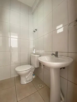 Foto do interior de um banheiro com revestimento cerâmico branco.