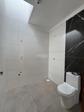 Ambiente de banheiro com revestimento branco e piso cinza.
