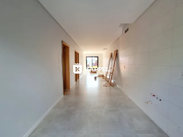 Foto de um corredor interno de uma residência com paredes brancas e piso claro.