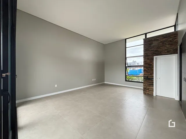 Vista interna de um espaço amplo com paredes cinzas e piso claro.