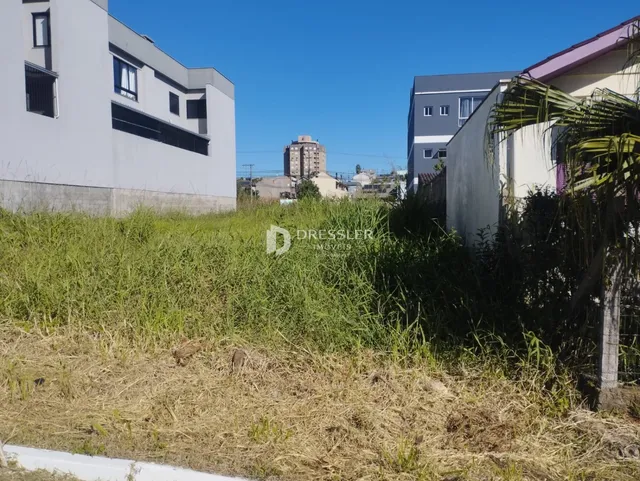 Fachada de imóveis em Lajeado, Brasil, com área de grama alta na frente.