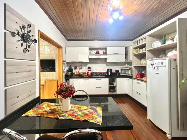 Foto de uma cozinha moderna com armários brancos e bancadas escuras.