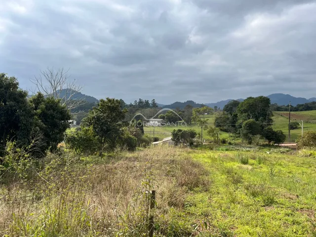 Vista panorâmica de campos e vegetação em uma paisagem rural sob um céu nublado.