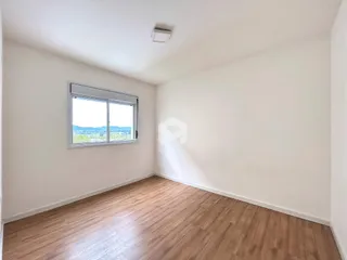 Ambiente interno de uma sala com piso de madeira e janela.