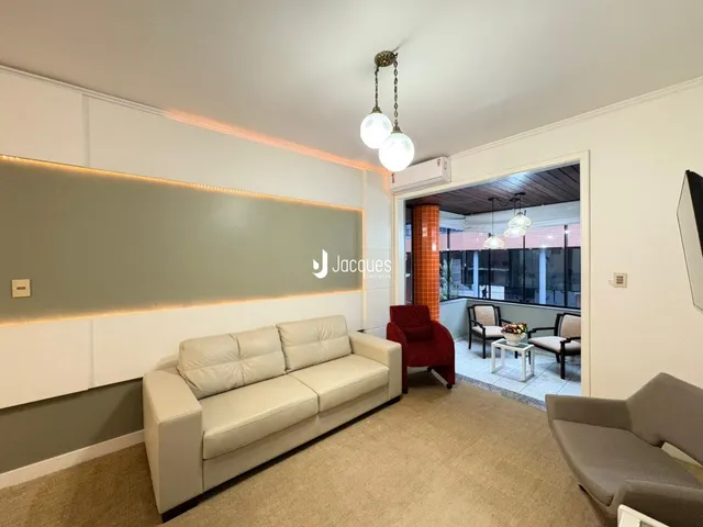 Sala de estar com sofá claro e iluminação de destaque na parede.
