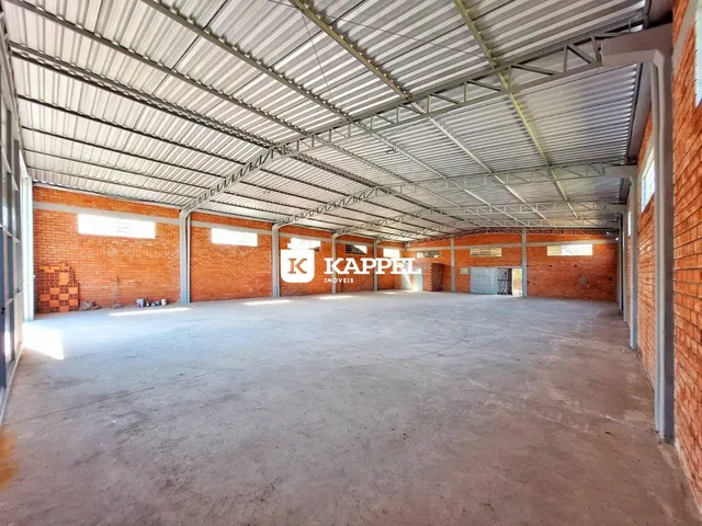 Foto de um espaço industrial amplo com estrutura metálica e paredes de tijolo aparente.