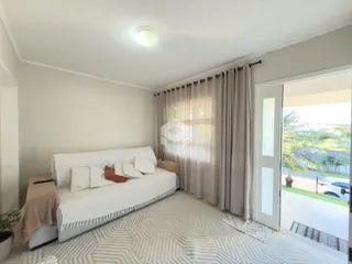 Sala de estar com sofá branco e cortinas claras em um imóvel no Brasil.