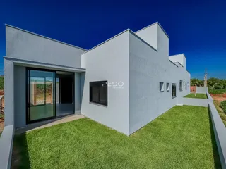 Fachada moderna de uma casa branca com jardim gramado.
