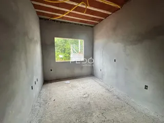 Interior de um cômodo com paredes de concreto e piso cru.