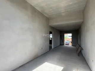 Corredor interno de uma residência com paredes brancas e piso de concreto.