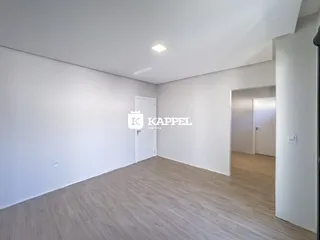 Ambiente interno com paredes brancas e piso de madeira clara.