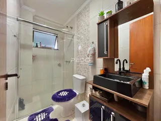 Banheiro com box de vidro e revestimento cerâmico na residência.