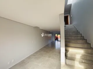 Corredor interno de uma residência com paredes brancas e piso claro.