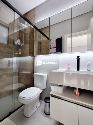 Banheiro com box de vidro e bancada branca.