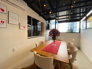 Uma sala de jantar com mesa de madeira e cadeiras brancas.
