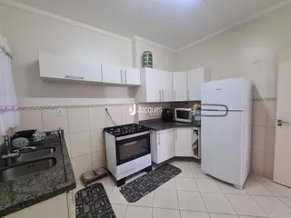 Foto de uma cozinha com armários brancos e revestimento cerâmico.