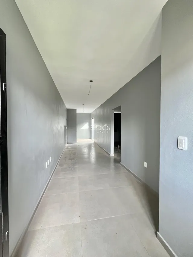 Corredor interno de uma residência com paredes cinzas e piso claro.