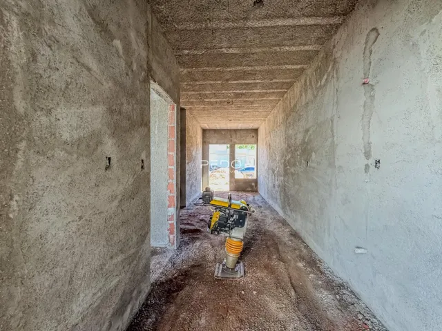 Corredor interno de uma residência com paredes de concreto aparente.