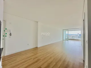 Ambiente interno de um apartamento com piso de madeira e vista panorâmica.