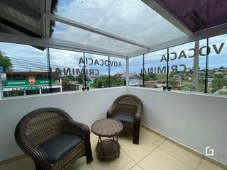 Varanda com duas cadeiras de vime e uma mesa redonda com vista para a rua.