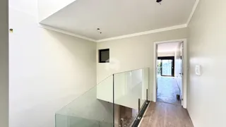 Vista de um corredor interno com parede branca e guarda-corpo de vidro.