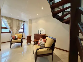 Sala de estar com janelas e móveis de madeira no interior da residência.