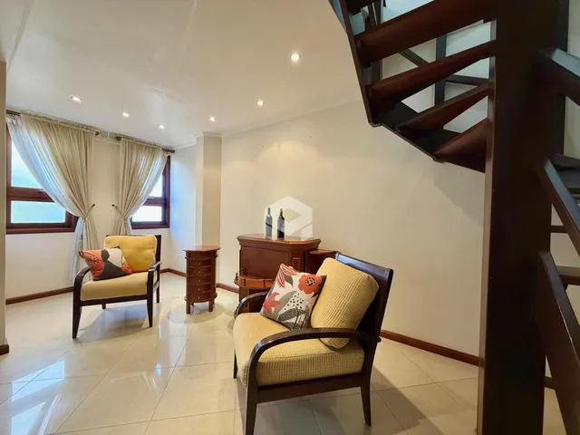 Sala de estar com janelas e móveis de madeira no interior da residência.