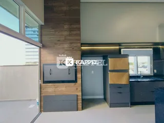 Sala de estar moderna com parede de madeira e área de cozinha integrada em apartamento em Lajeado.