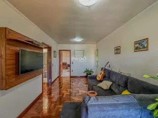 Sala de estar com piso de madeira e sofá cinza.