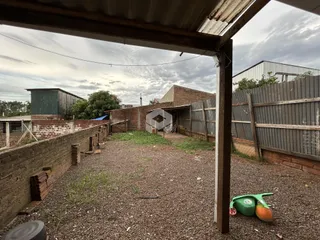 Vista externa de um terreno com muros de tijolo e cercas de metal.