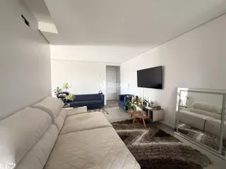 Sala de estar com sofá e televisão em ambiente claro.