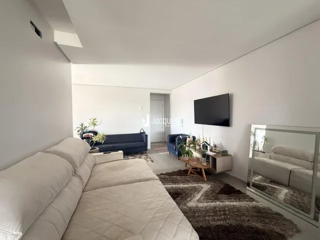 Sala de estar com sofá e televisão em ambiente claro.