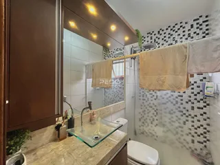Foto de um banheiro com revestimento de azulejos e bancada de vidro.
