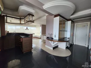 Vista de uma cozinha moderna com ilha central e piso escuro.