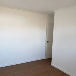 Foto de uma parede branca e piso de madeira em um interior.