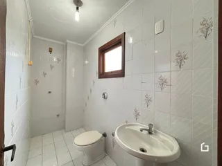 Banheiro com paredes brancas e piso de cerâmica.