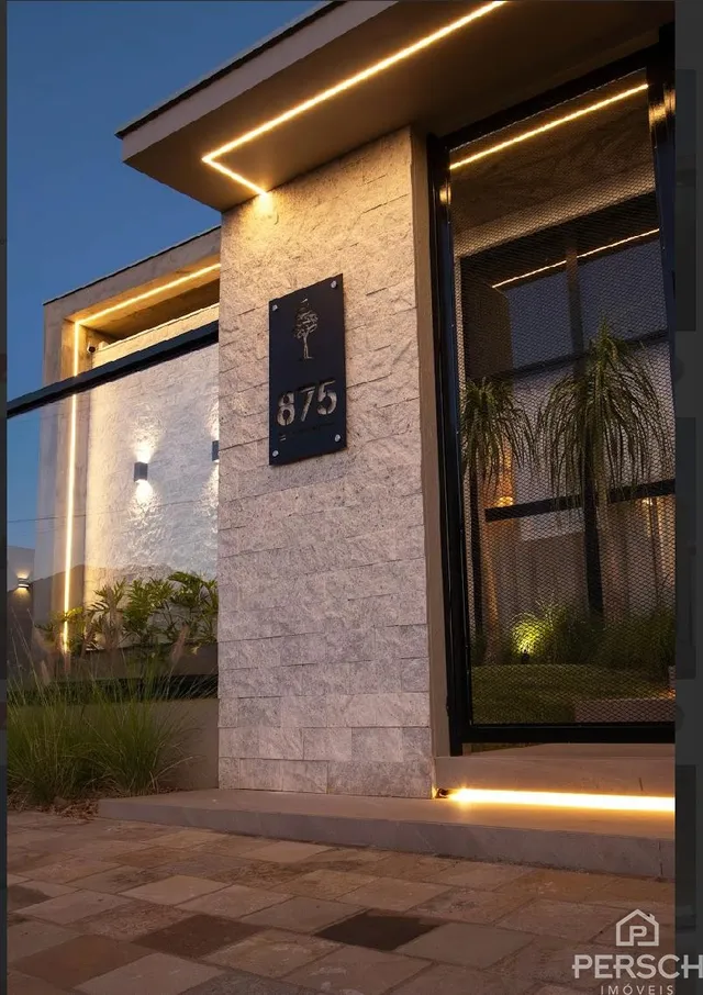 Fachada de uma residência com iluminação noturna destacando a entrada.
