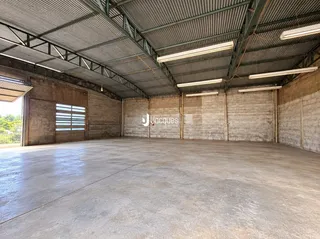 Espaço industrial amplo com teto metálico e piso de concreto.