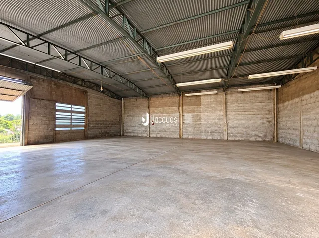 Espaço industrial amplo com teto metálico e piso de concreto.
