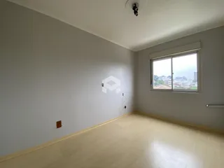 Ambiente interno de uma sala com piso de madeira clara e paredes brancas.