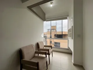 Sala de estar com duas poltronas e grande janela em um apartamento.
