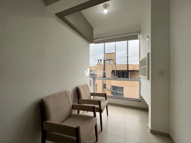 Sala de estar com duas poltronas e grande janela em um apartamento.