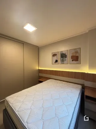 Quarto com cama grande e painel de madeira na parede.
