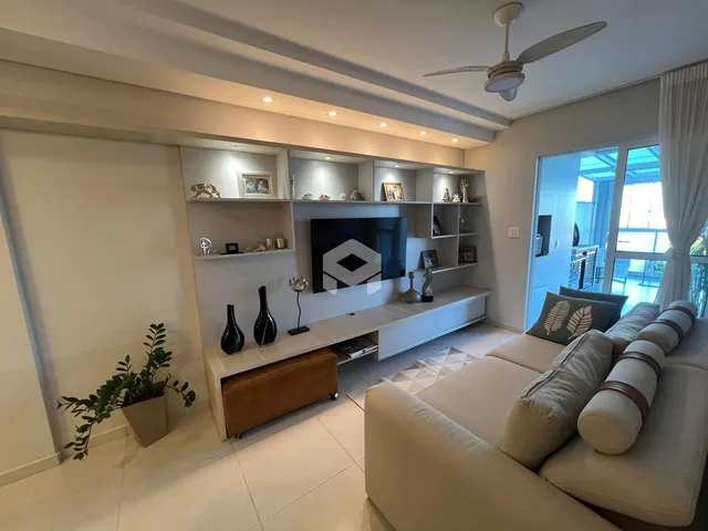 Sala de estar moderna com sofá e painel de TV em um apartamento no Brasil.