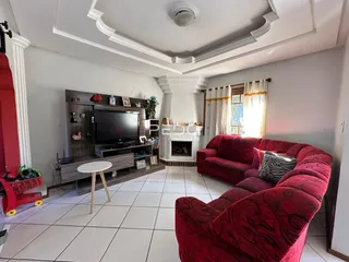 Sala de estar com sofá vermelho e lareira em um imóvel no Brasil.