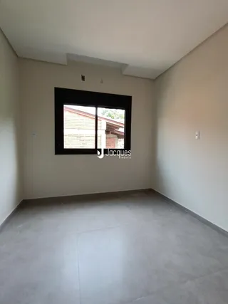 Ambiente interno de uma sala com parede clara e piso de concreto.