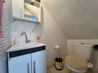 Foto de um banheiro com bancada branca e revestimento de azulejo.