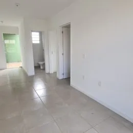 Corredor interno com piso claro e paredes brancas.