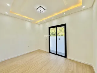 Sala de estar com piso de madeira clara e porta de vidro.